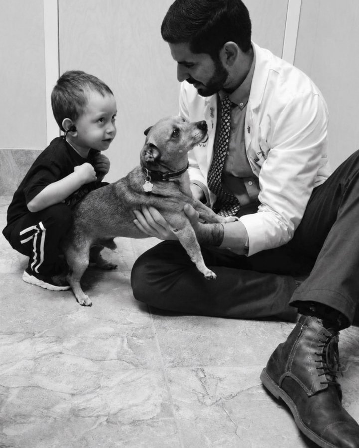 Dr. Manuel Lima kneeling with a young boy and a small dog at Flora Family Vet
